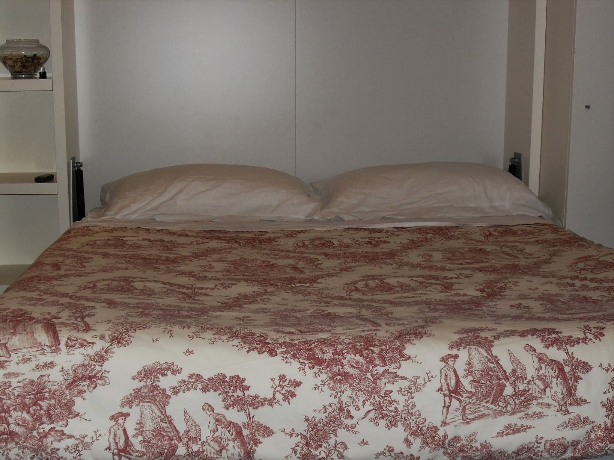Un lit avec une couvre-lit à motifs floraux et deux oreillers.