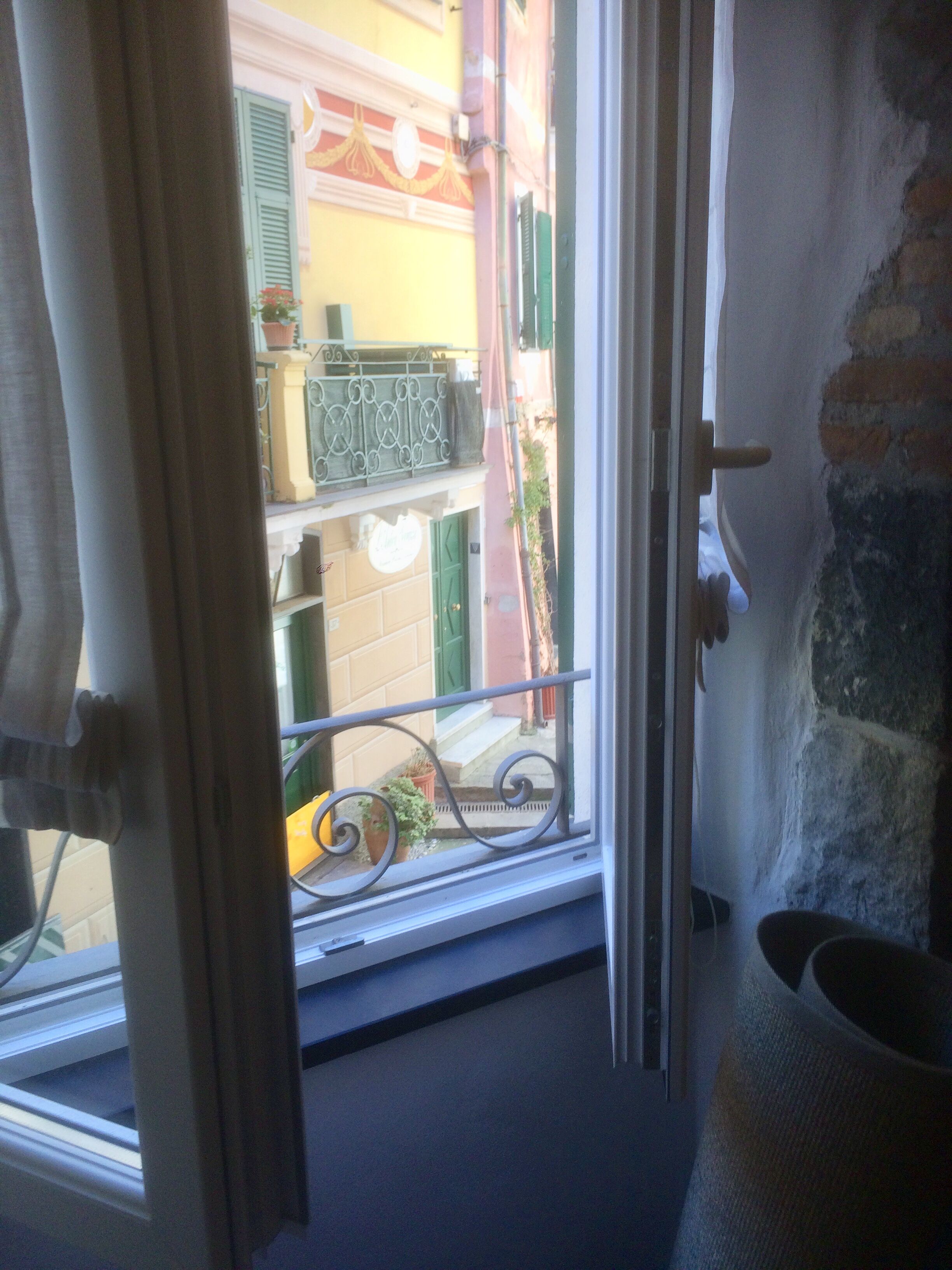 Una ventana con vistas a un edificio con contraventanas verdes y un balcón.