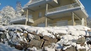 Un edificio de varios pisos con balcones y un muro de piedra al frente.