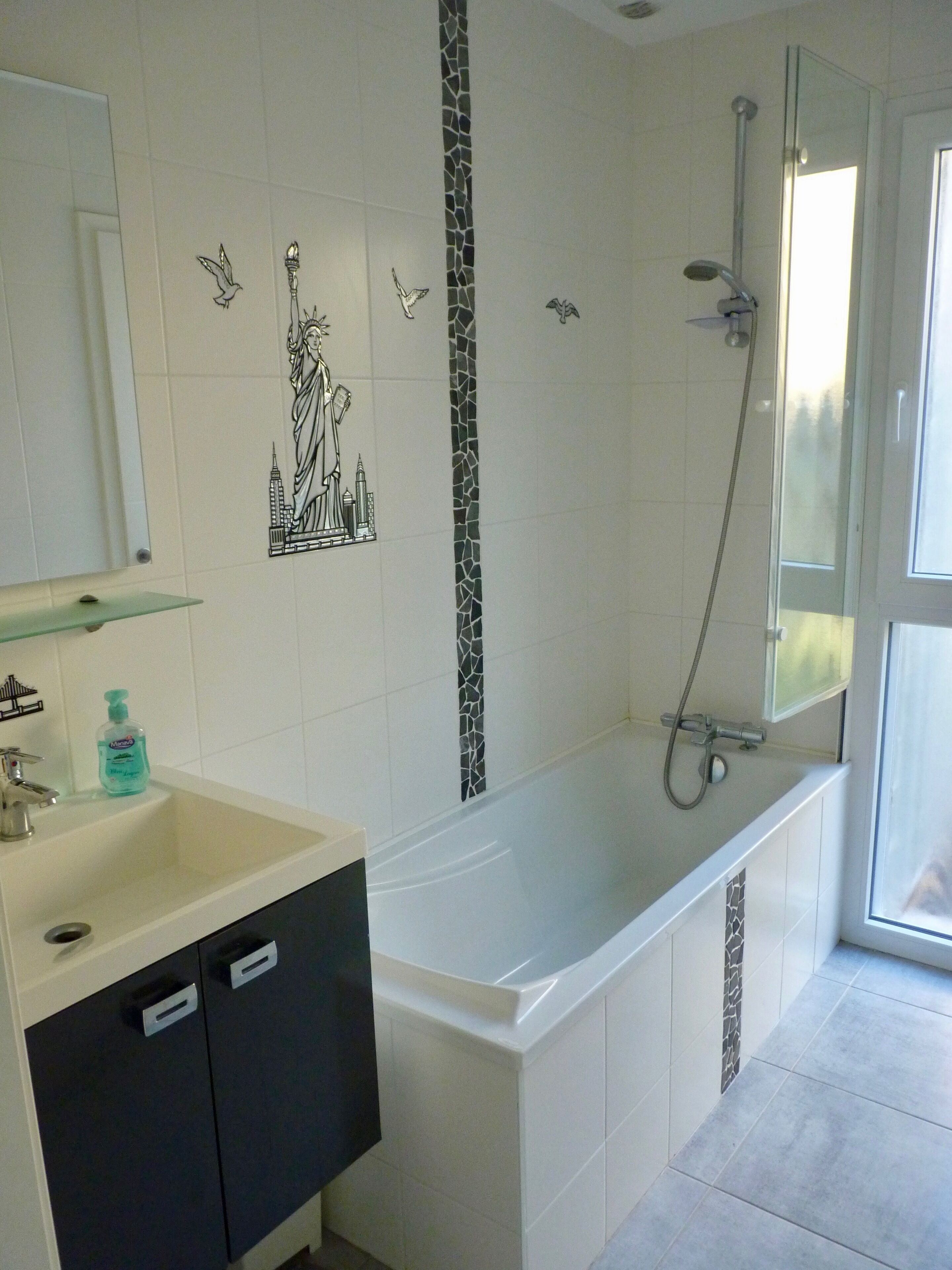 A bathroom with a white sink, black cabinets, a bathtub, and a shower.