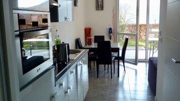 A modern kitchen with a dining area, large windows, and a view of the outdoors.