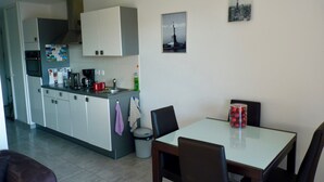 Cocina compacta con comedor, que incluye refrigerador, microondas, lavamanos y una pequeña mesa de comedor con sillas.