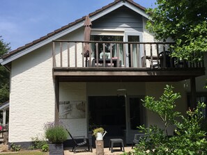 Een huis met twee verdiepingen, een balkon, een overdekte veranda en een tuin.