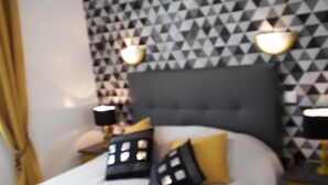 Ein Schlafzimmer mit einem Bett, zwei Nachttischen, einem Kopfteil und einer Wand mit geometrischem Muster.