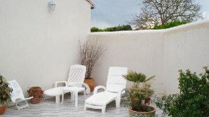 Eine Terrasse mit weißen Lounge-Sesseln und Topfpflanzen.