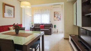 A modern living room with a glass dining table, a brown sofa, and a television. - MARQUES, renovated, large, modern, 4 bedrooms flat for rent by days in Barcelona center, Eixample, Sant Antoni (Barcelona)