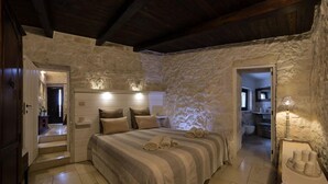 A bedroom with a stone wall, a bed with striped bedding, and a nightstand.