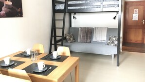 A bunk bed with a ladder, a table with cups and a glass, and a door with a sign. - Casa Cervinia Apartment  (Breuil Cervinia)