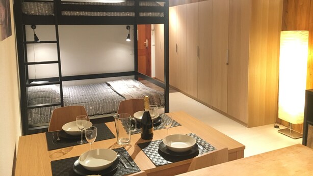 A dining area with a wooden table set for four, a bunk bed in the background, and a wooden wardrobe. - Casa Cervinia Apartment  (Breuil Cervinia)