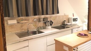A modern kitchen with a stainless steel sink, a kettle, a toaster, and a small refrigerator. - Casa Cervinia Apartment  (Breuil Cervinia)