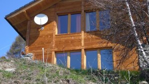 Une cabane en bois avec un toit en pente, une antenne parabolique et de nombreuses fenêtres.