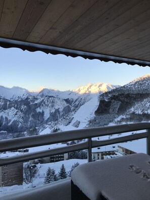 Un balcon offrant une vue sur des montagnes enneigées et doté d’un plafond en bois.
