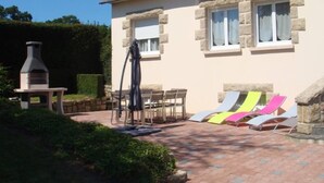 A house with a patio area featuring a grill, outdoor furniture, and colorful sun loungers. - House / Villa - MORIEUX (Morieux)