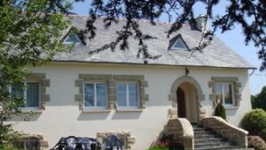 A two-story house with a stone facade, a central entrance with a small porch, and a staircase leading to the main entrance. - House / Villa - MORIEUX (Morieux)