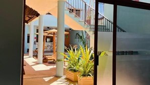 A modern building with large glass doors leading to an outdoor area with potted plants and a staircase. - Paraiso Azul Hotel (Loreto)