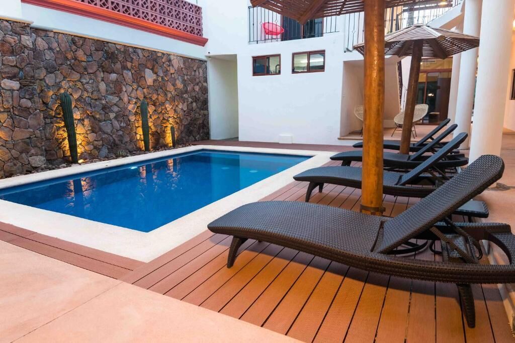 A swimming pool with lounge chairs and a stone wall.
