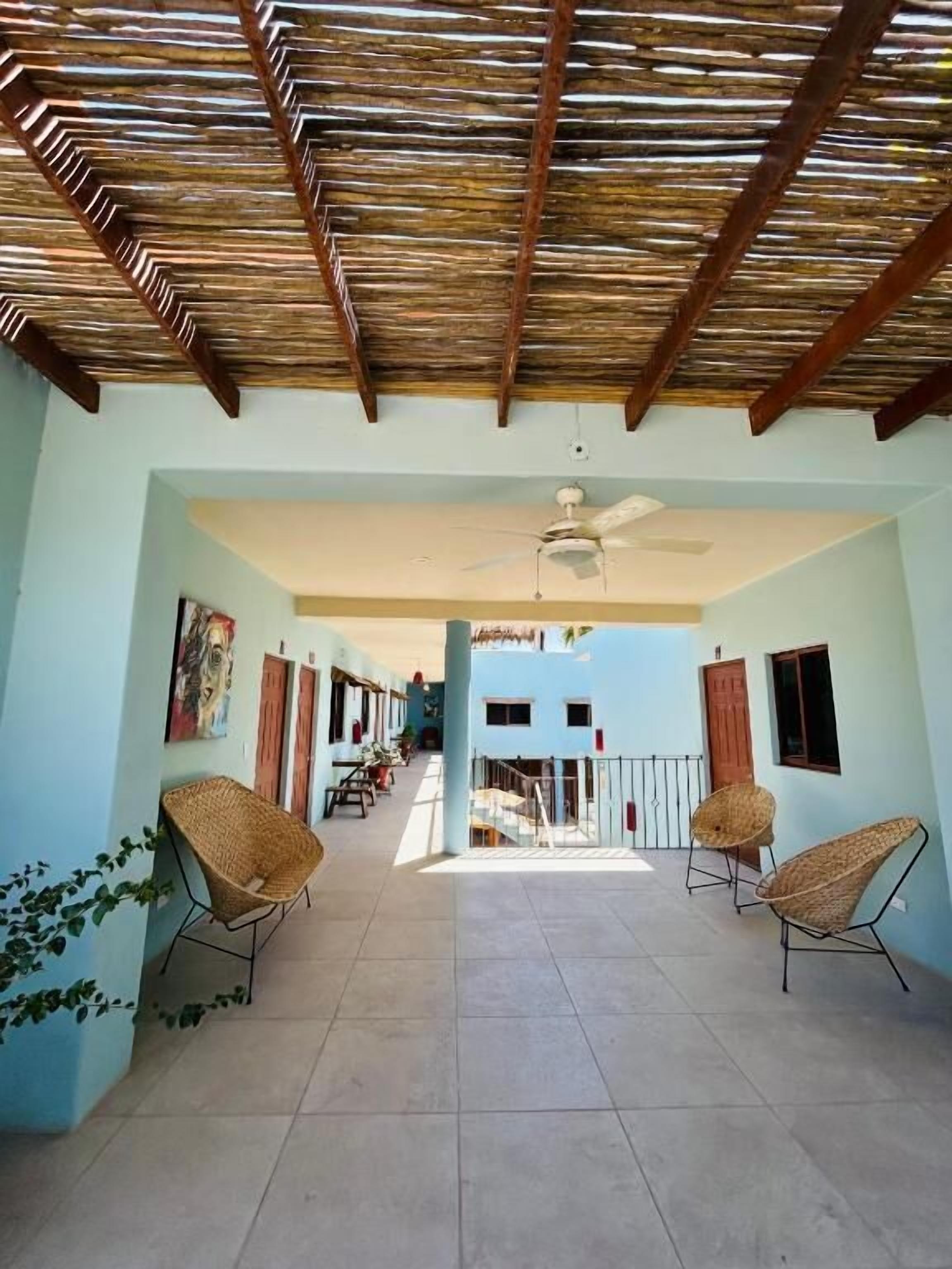 A covered patio area with a ceiling fan, wicker chairs, and a tiled floor.