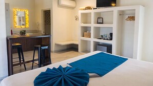 A hotel room with a bed, a desk with two chairs, a TV, a wardrobe, and a shelf with various items. - Paraiso Azul Hotel (Loreto)