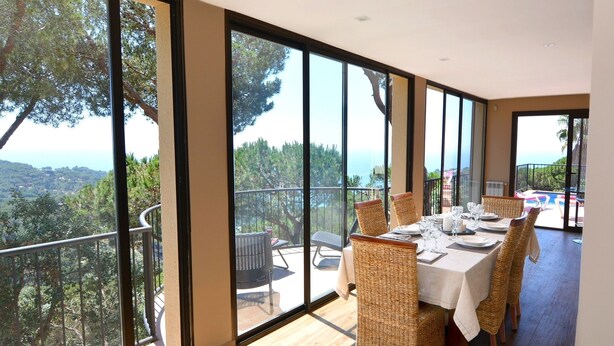 A dining area with a view of the landscape through large windows. - FANTASTIC SEA VIEWS  (Lloret de Mar)
