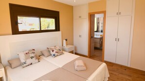 A bedroom with a bed, bedside tables, a wardrobe, and a bathroom visible through an open door. - FANTASTIC SEA VIEWS  (Lloret de Mar)