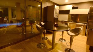 A modern kitchen with a glass partition, stainless steel appliances, and a dining area with bar stools. - FANTASTIC SEA VIEWS  (Lloret de Mar)
