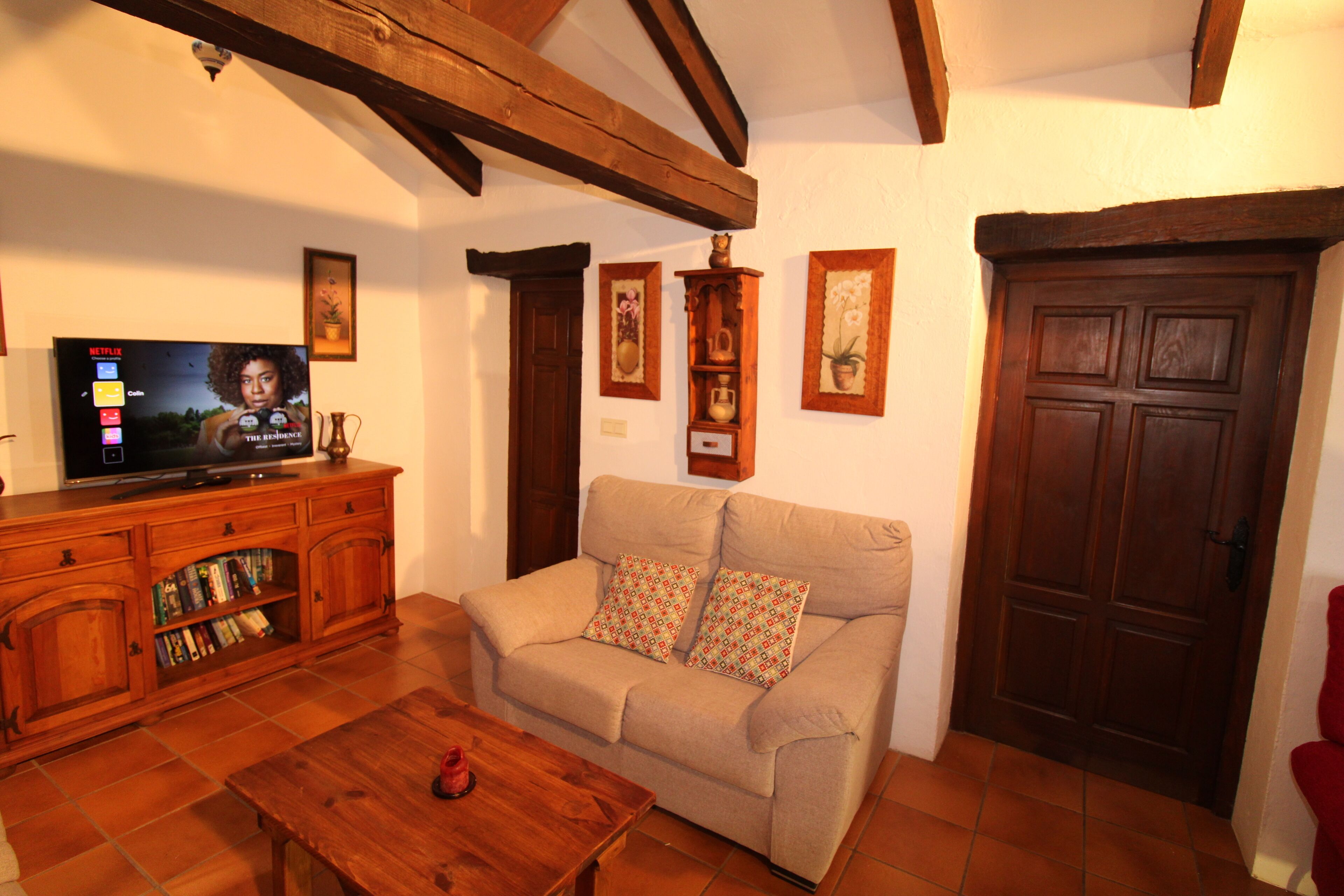 Una sala de estar con sofá, mesa de centro de madera y televisor sobre mueble de madera.