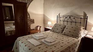 A bedroom with a bed, a nightstand, a lamp, a wooden wardrobe, and a checkered floor. - Rural Accommodations Casa Fabián, La Cabaña (Pet Friendly)  (Castrillón)