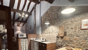 A kitchen with a checkered floor, a stone wall, and a wooden ceiling. - Rural Accommodations Casa Fabián, La Cabaña (Pet Friendly)  (Castrillón)