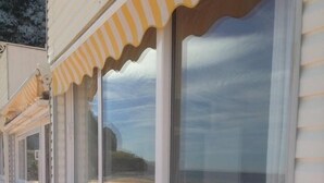 Un bâtiment à la façade blanche, doté de grandes fenêtres et d’un auvent rayé jaune et blanc.