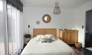 Un dormitorio con una cama grande, un armario de madera, una lámpara colgante y un espejo en la pared.