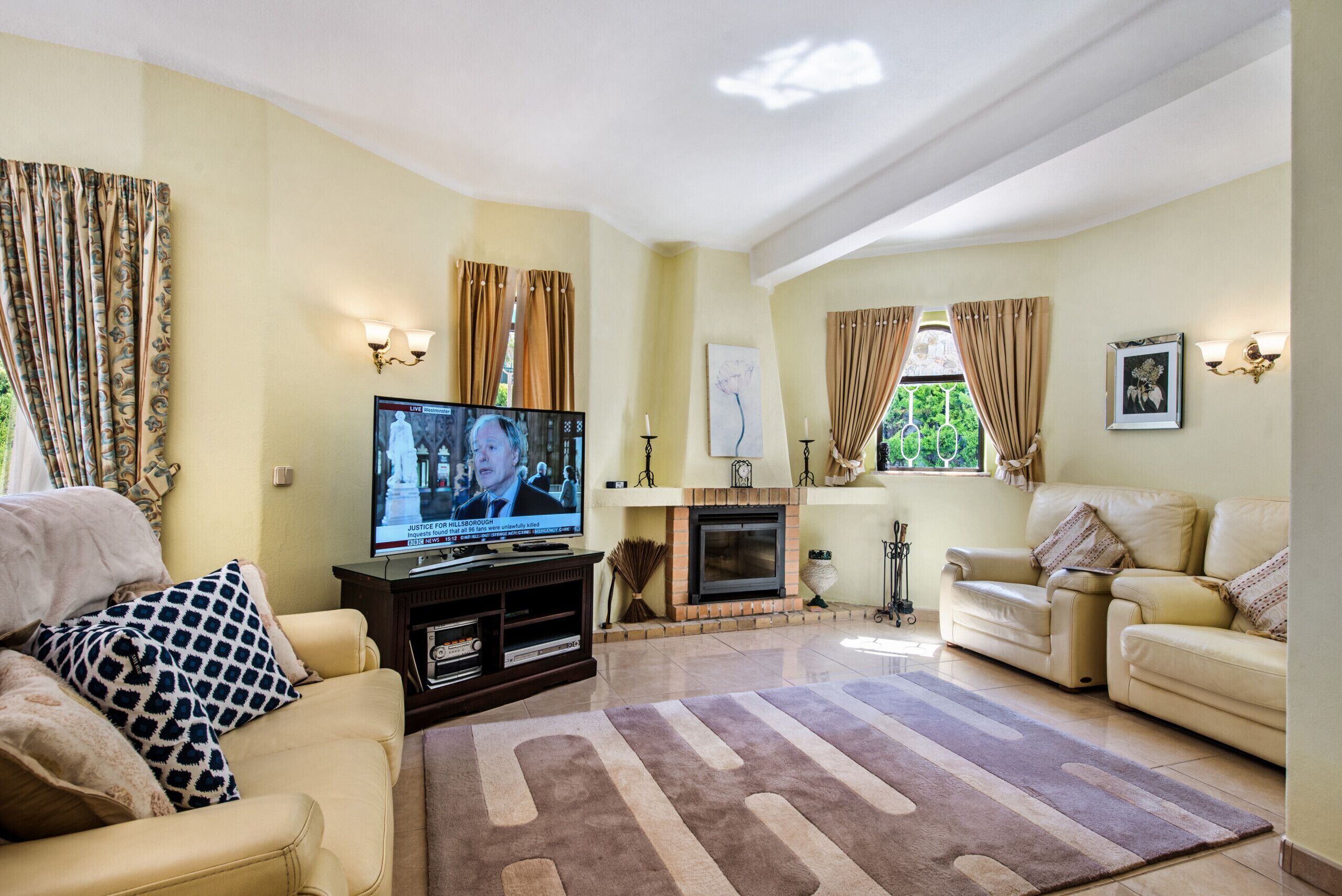 Un salon avec une télévision, un canapé et une cheminée.