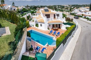 A residential property with a swimming pool, lounge chairs, and a patio area.