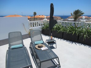 A rooftop terrace with two lounge chairs, a table with a bottle and glass, and a view of the sea and buildings. - LAS ROSAS by RENTMEDANO, stunning luxury Chocolate Box Villa (El Medano)