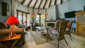 A cozy living room with a sofa, a wicker chair, a coffee table, and a fireplace. - Family holiday house directly at sea (Calp)