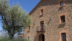 Un bâtiment en pierre avec un grand arbre devant.