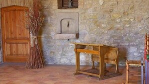 Une pièce rustique avec un mur en pierre, une porte en bois, une petite table et un balai.