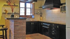 Une cuisine dotée d’un îlot central en pierre, de meubles de rangement noirs, d’un four encastré et d’un four à micro-ondes.