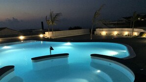 A swimming pool with a flag marker, surrounded by a low wall and palm trees. - New 4 bed villa in Zambrone - Spectacular 180 degree panoramic sea views. (Zambrone)