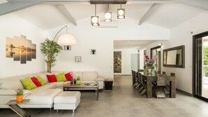 A modern living room with a sectional sofa, a coffee table, and a dining area with a wooden table and chairs.