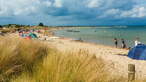 Uma praia com tendas, barcos e pessoas.