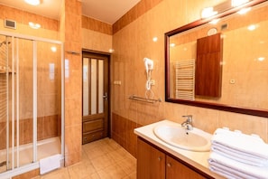 Een moderne badkamer met een douchecabine van glas, een wastafel met spiegel en een handdoekrek.