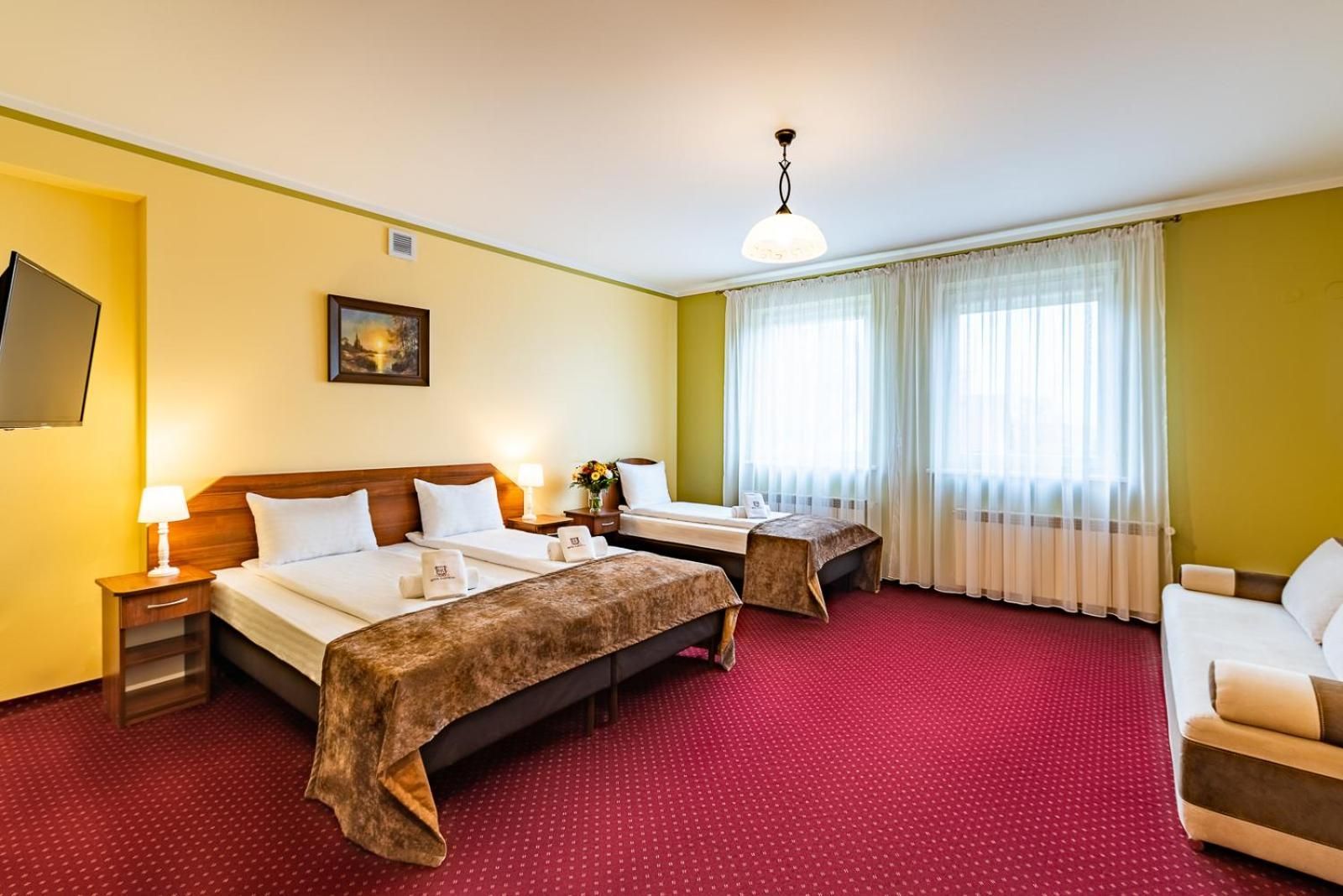 Una habitación de hotel con dos camas, un sofá, un televisor y un cuadro en la pared.