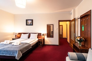 A hotel room with a bed, bedside tables, a mirror, a red carpet, a wooden wardrobe, and a door with a green sign. - Hotel Kasztelan (Dobczyce)