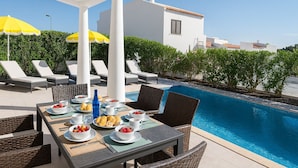 A poolside dining area with a table set for two, surrounded by lounge chairs and umbrellas. - Villa Sete, Beautiful Spacious Private 5 Bedroom Villa, Albufeira Town (Albufeira)