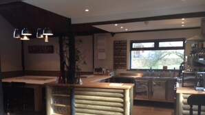 A cozy kitchen with a wooden island, a large window, and a sign reading "Café Latte Macchiato Cappuccino".