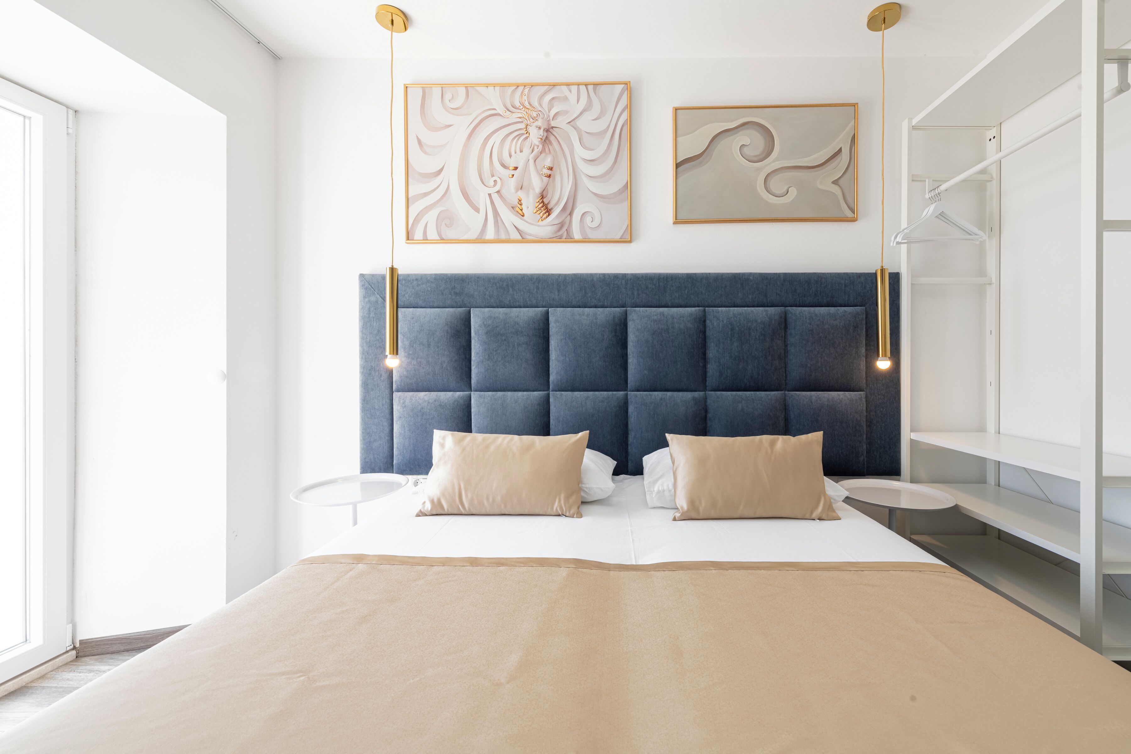 A modern bedroom with a large bed, a tufted headboard, and two wall-mounted light fixtures.
