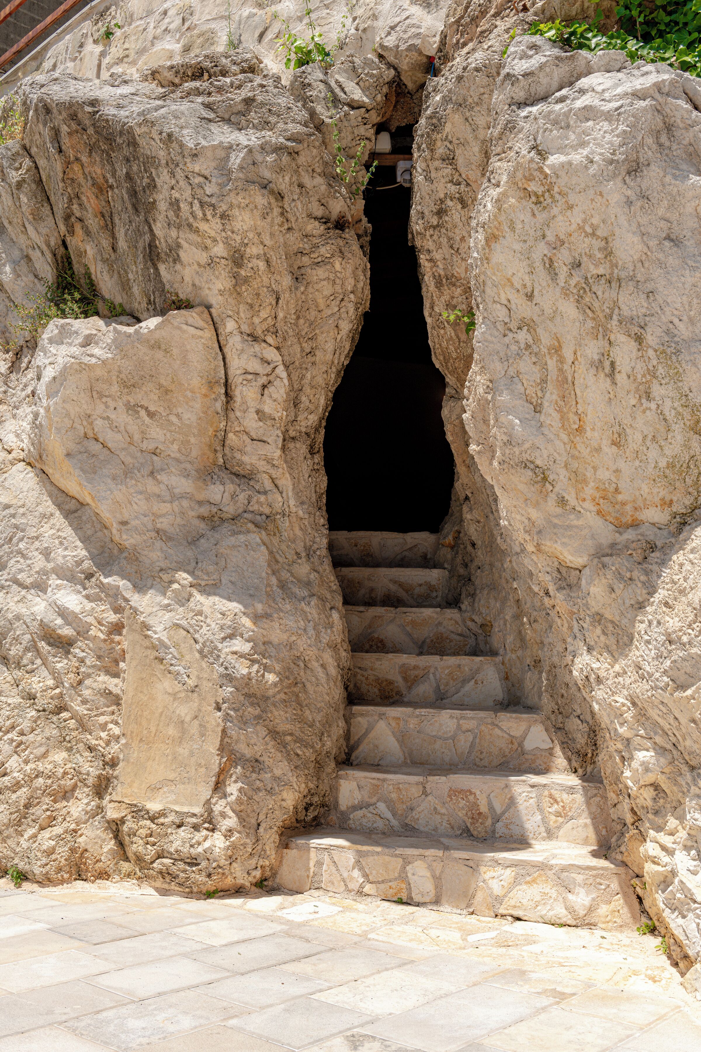 A set of stone steps leading into a dark opening between large rock formations.