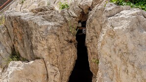 Une série de marches en pierre menant à une ouverture sombre entre de grandes formations rocheuses.