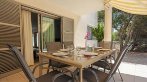 A dining area with a glass table, chairs, and a yellow umbrella. - Large aloe house (Son Serra de Marina)