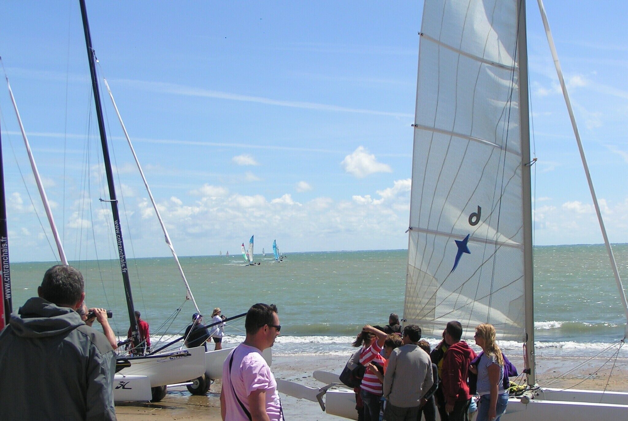 Un velero amarrado en la playa, con gente reunida alrededor.